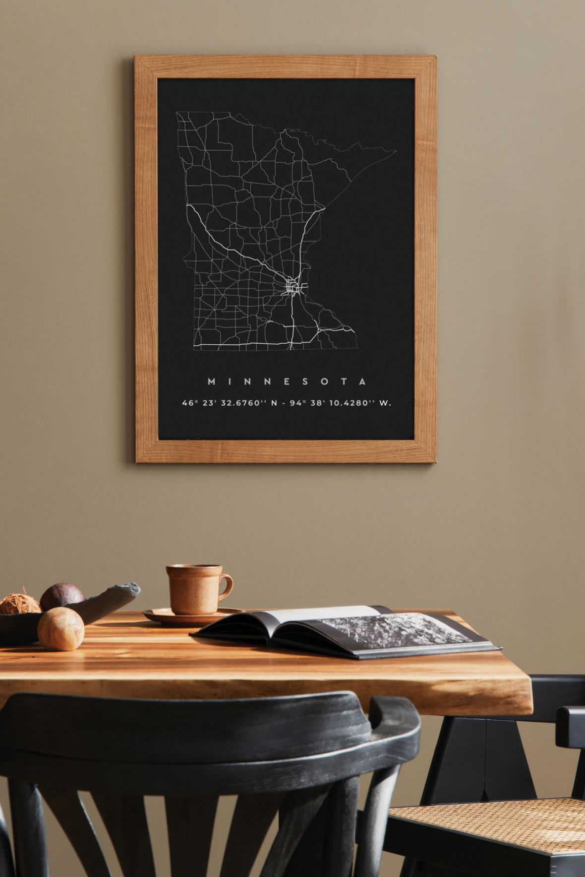 Modern dining room with a wooden table, black chairs, candles, and a Minnesota map on the wall.