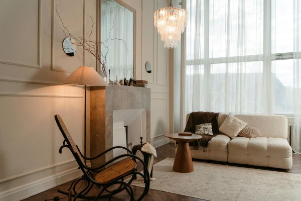 Elegant living room with a cozy sofa, rocking chair, fireplace, and large window with sheer curtains.